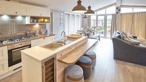 A modern kitchen with a central island, a dining area with a table and chairs, and a cozy seating area with a sofa and ottomans.