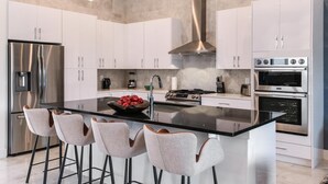 Uma cozinha moderna com uma ilha central, eletrodomésticos de aço inoxidável e armários brancos.