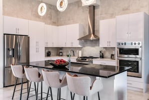 Une cuisine moderne dotée d’un îlot central, d’appareils électroménagers en acier inoxydable et de meubles blancs.