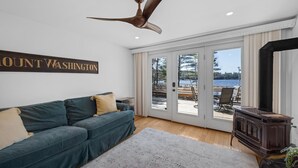 A living room with a green sofa, a ceiling fan, a sign reading "Mount Washington," and a view through glass doors to an outdoor deck.