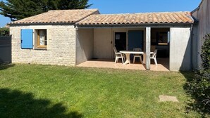 A small house with a tiled roof, a stone exterior, and a patio with a table and chairs. - LE CLOS DE DOMINO (Saint-Georges-d'Oléron)