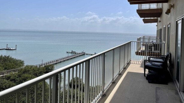 A balcony with a view of the sea and a dock.
