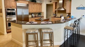 A modern kitchen with wooden cabinets, stainless steel appliances, and a central island with bar stools.