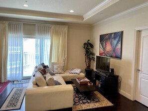 A living room with a sofa, coffee table, TV, and artwork. - Laguna Bay 302n 3 Bedroom Condo by RedAwning (South Padre Island)