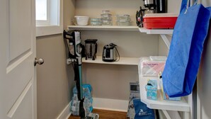 A compact kitchen with white shelves, a coffee maker, and a vacuum cleaner. - Makani Ea Home 2 Bedroom Home by RedAwning (Hakalau)