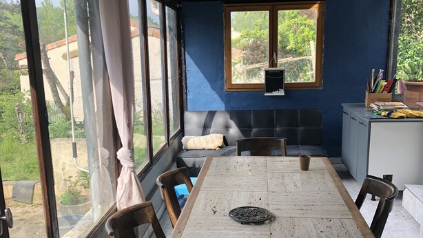 Un comedor con una mesa larga, sillas, un banco y vistas al exterior.
