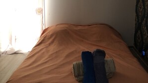 Un dormitorio con una cama individual, una ventana con cortinas florales y un papel tapiz estampado.