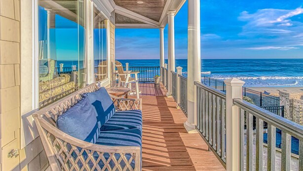 A covered balcony with a wooden floor, white railings, and a view of the ocean. - Luxury Home with Private Pool and Stunning Views (Garden City Beach)