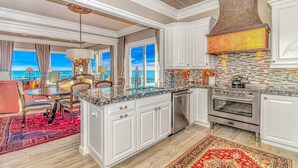 A spacious kitchen with a large island, white cabinetry, and a view of the ocean. - Luxury Home with Private Pool and Stunning Views (Garden City Beach)
