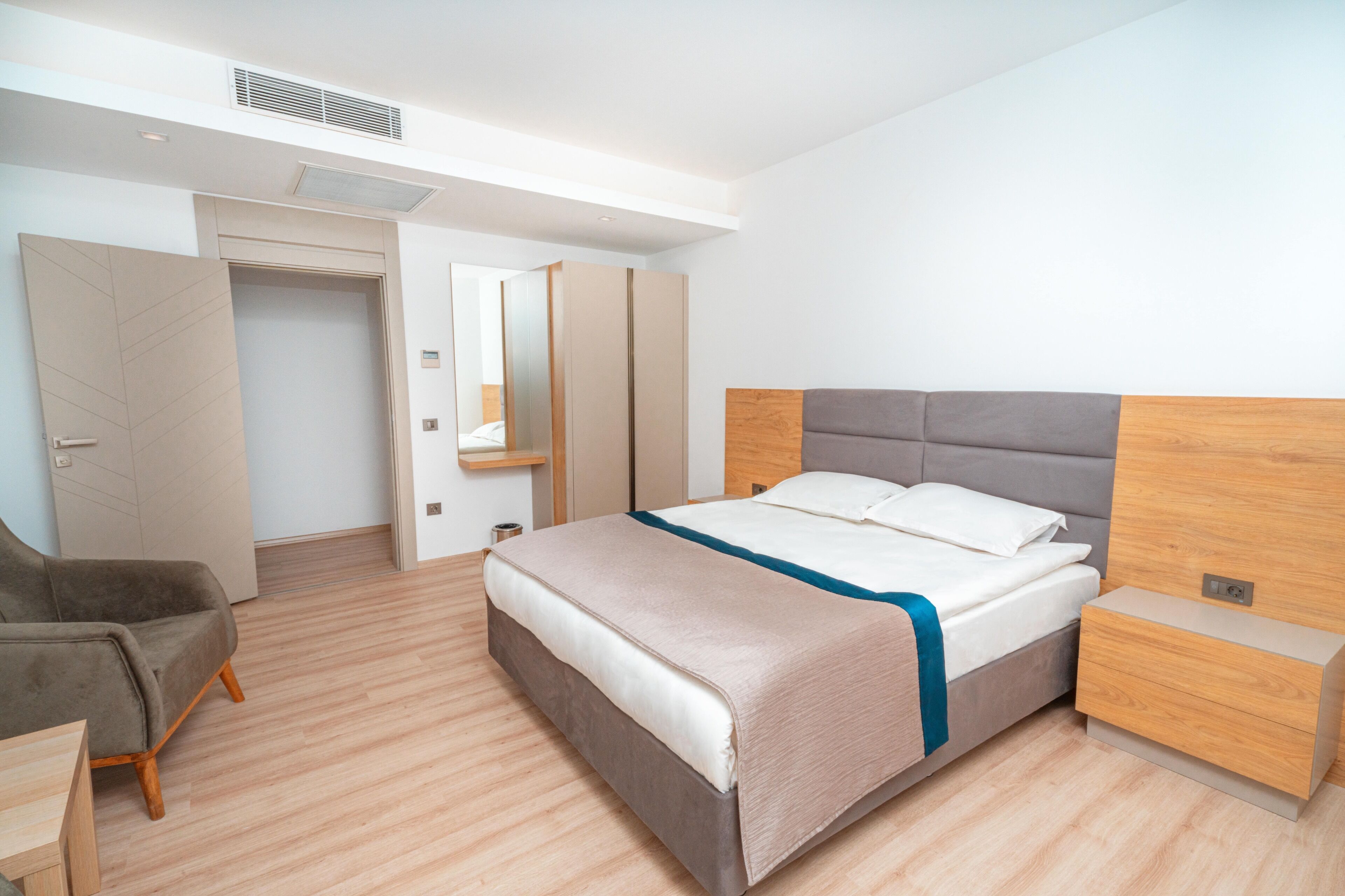 A modern bedroom with a bed, bedside table, and a chair.