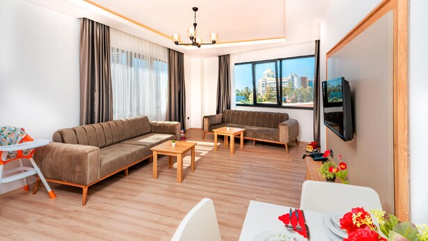 A modern living room with a sofa, two coffee tables, a dining table set for two, and a TV mounted on the wall.