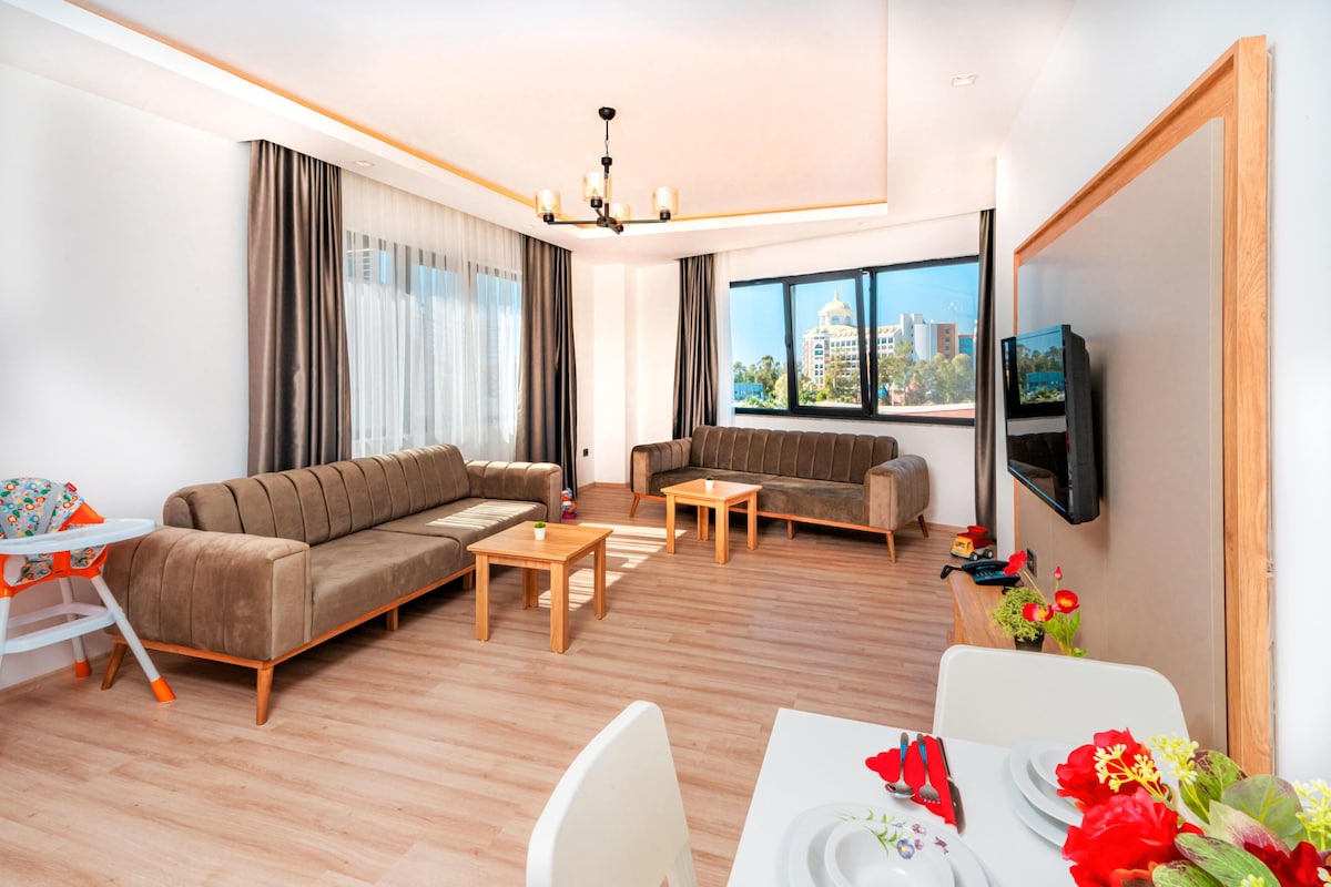 A modern living room with a sofa, two coffee tables, a dining table set for two, and a TV mounted on the wall.