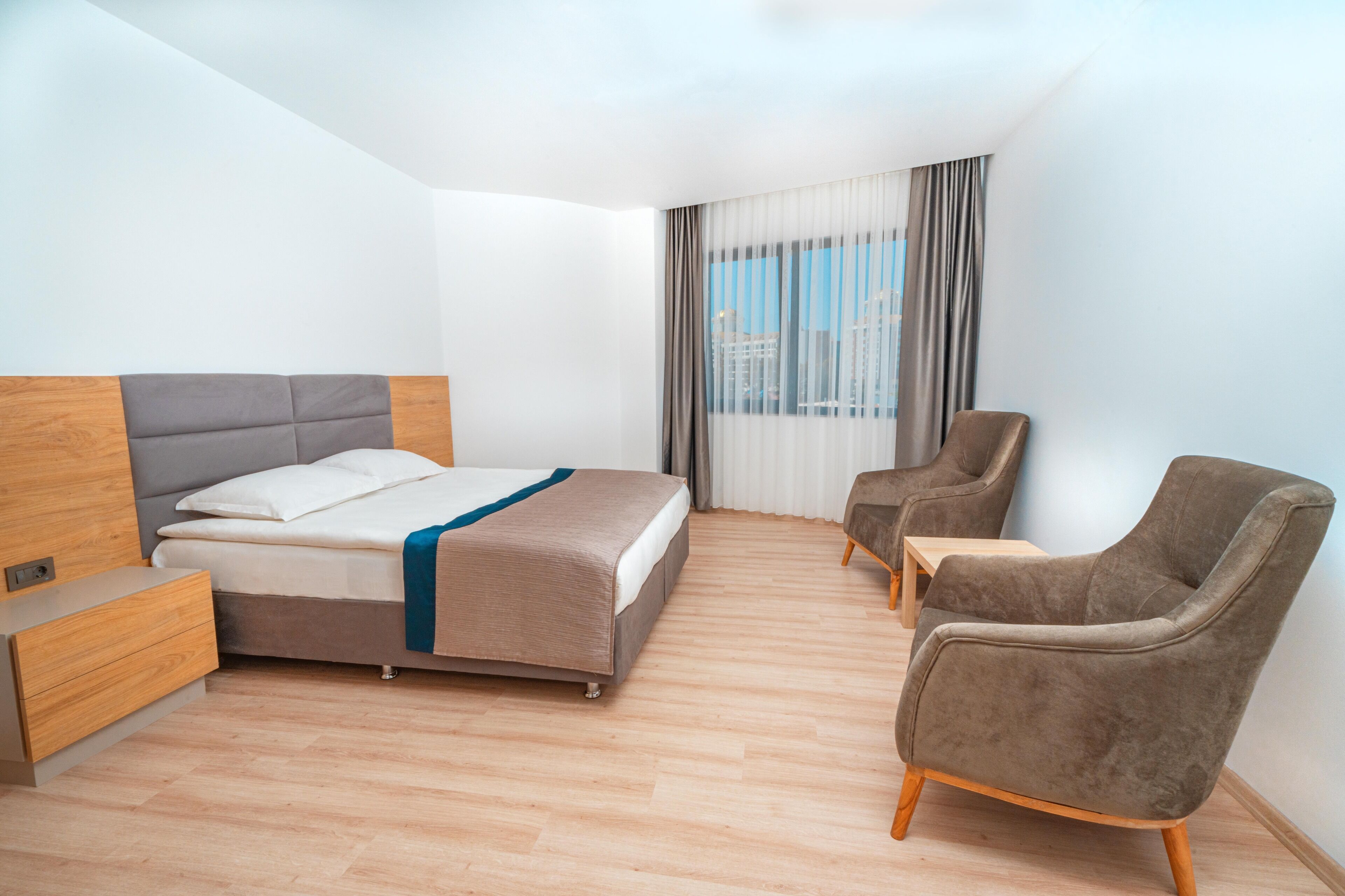 Ein modernes Hotelzimmer mit einem Bett, einem Schreibtisch und zwei Sesseln.
