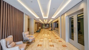 A hallway with plush seating, a polished marble floor, and a modern ceiling design.