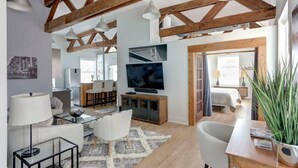 Een modern interieur met zichtbare houten balken, een flatscreen televisie, een eethoek en een badkamer.