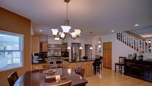 A spacious kitchen with a dining area, wooden cabinets, and a large island. - Hawaiian Dream with Pool (Pepeekeo)
