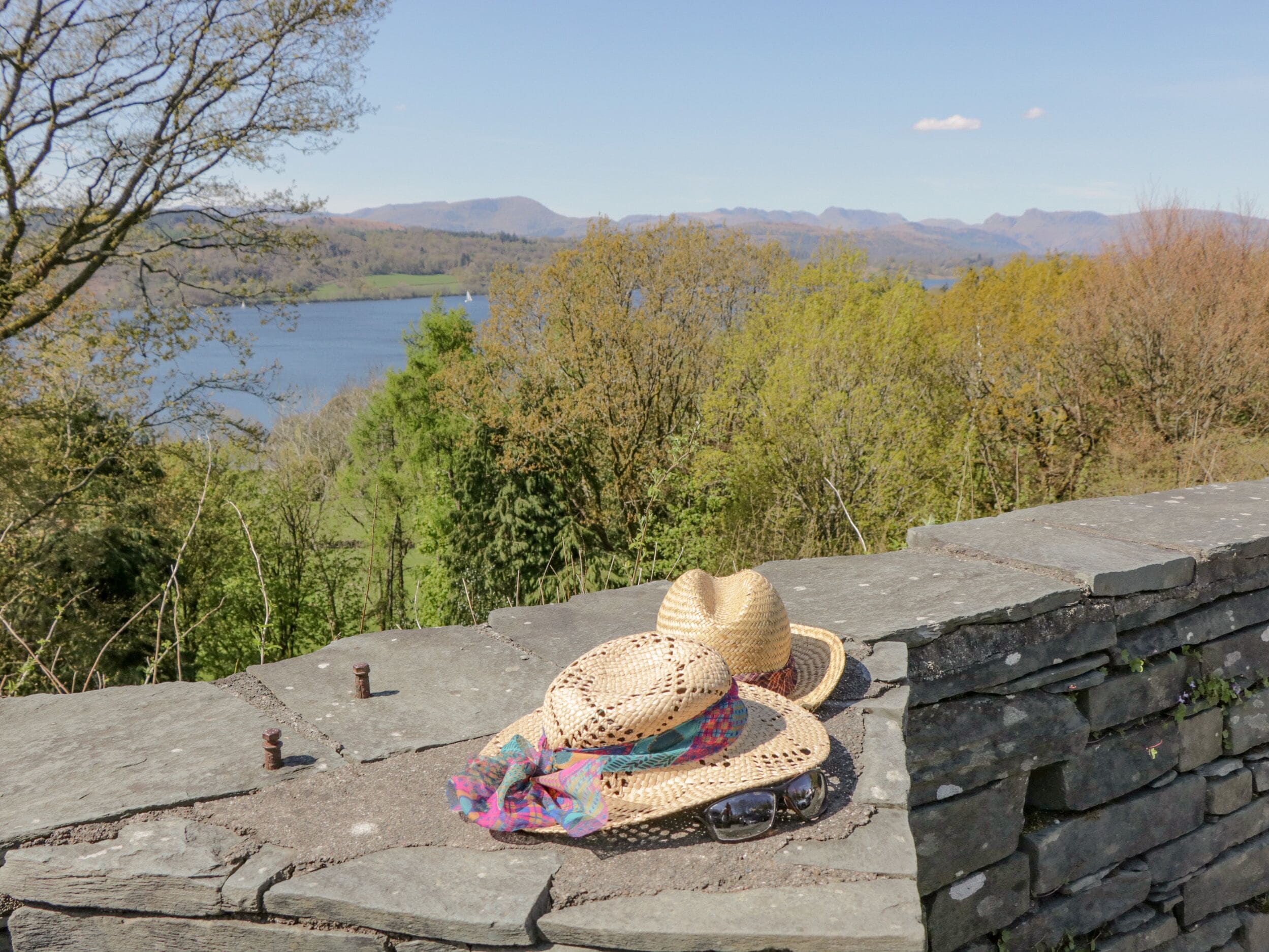 A stone wall with a straw hat and sunglasses placed on it.