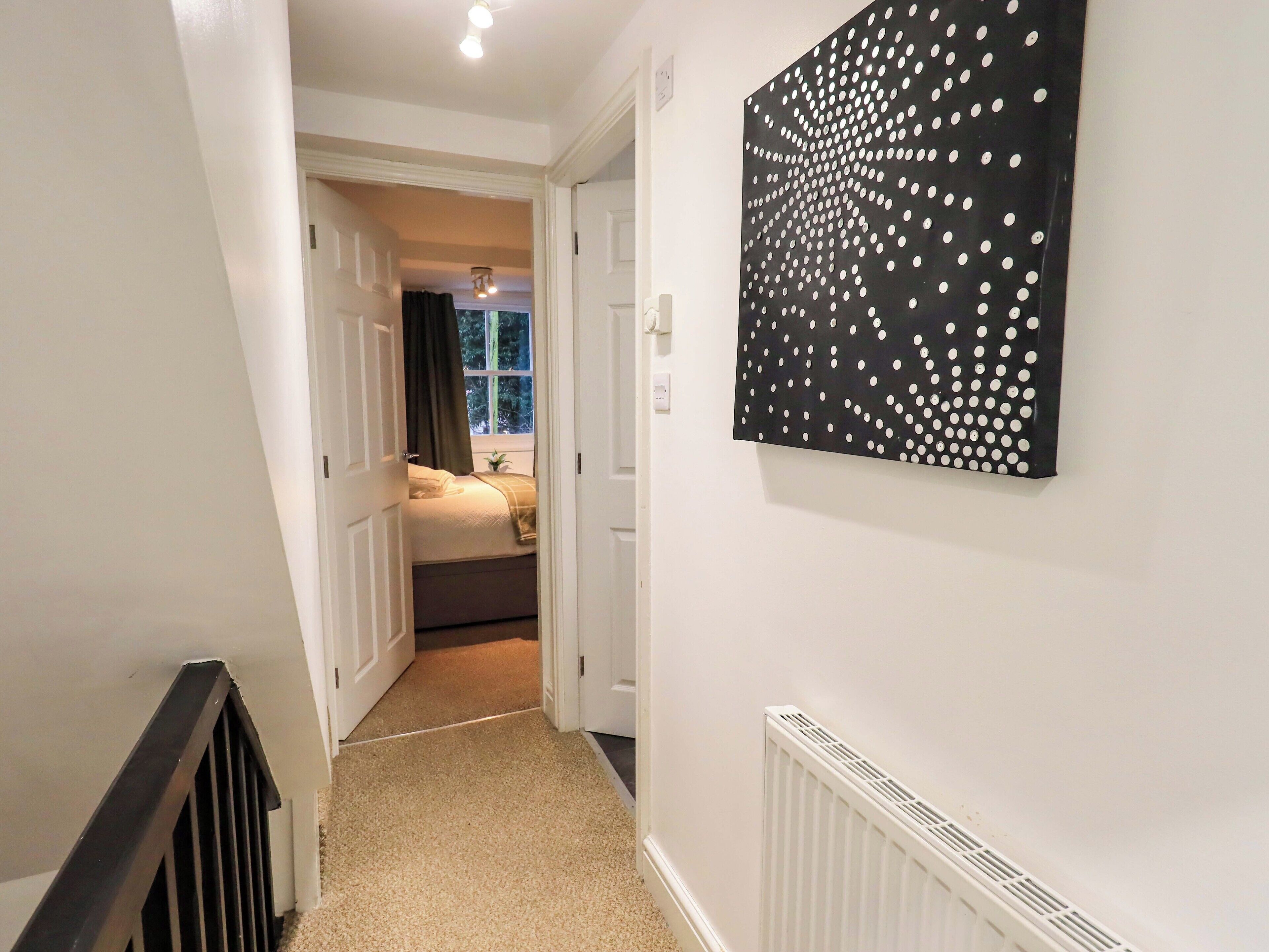 A hallway leading to a bedroom with a radiator and a polka dot wall art.