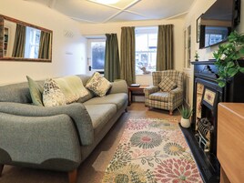 Una sala de estar acogedora con sofá, sillón y alfombra estampada.