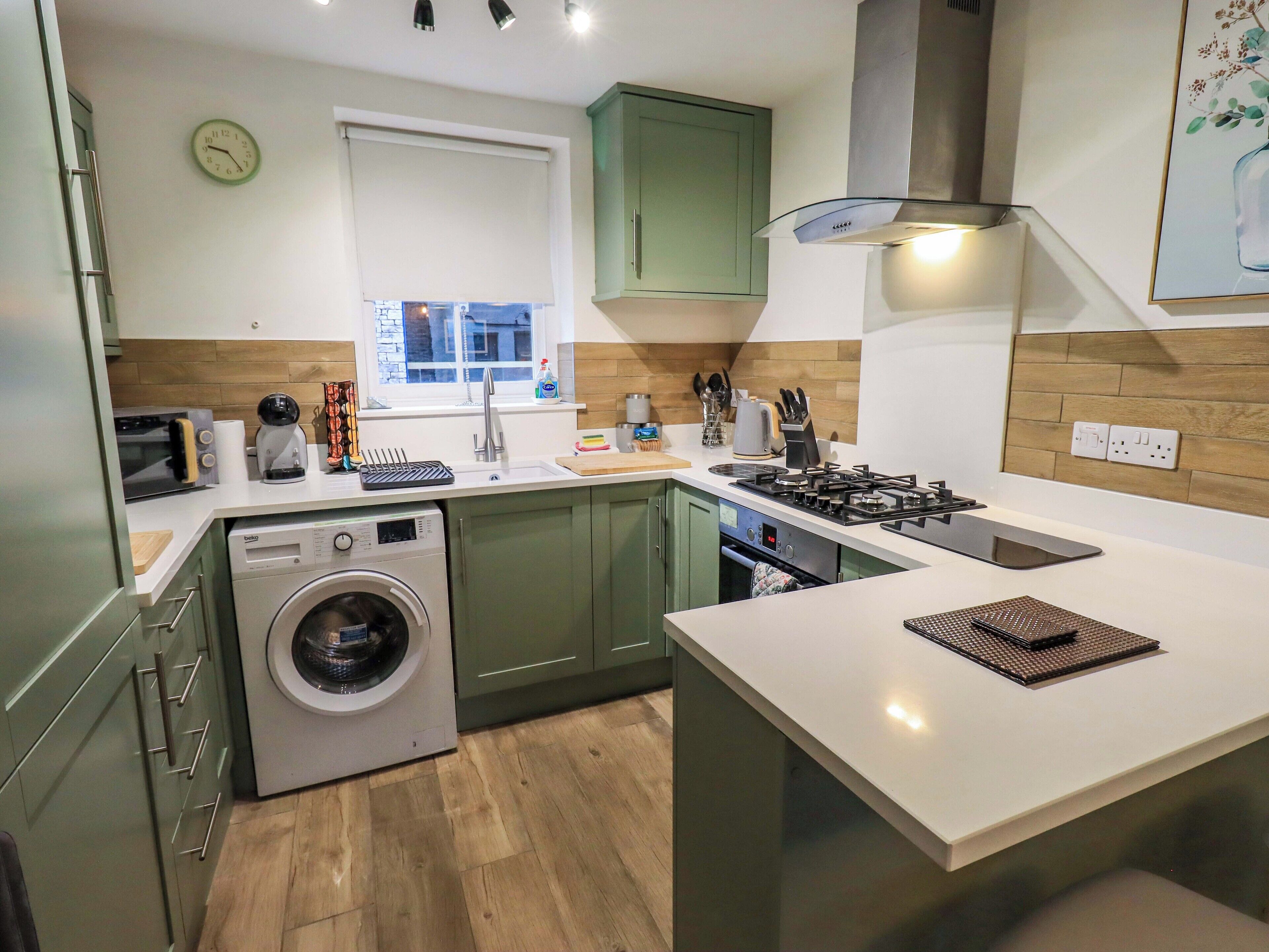 A modern kitchen with a built-in washing machine, a stove, and a sink.
