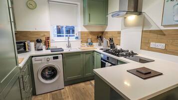 A modern kitchen with a built-in washing machine, a stove, and a sink.