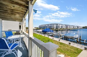 Une propriété située au bord de l’eau, dotée d’une terrasse couverte, d’un espace salon extérieur et offrant une vue sur une marina et les bâtiments situés de l’autre côté.