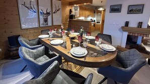 Un comedor con paneles de madera y una gran mesa redonda dispuesta para seis personas, rodeada de sillas con cojines.
