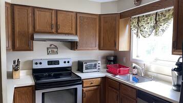 Une cuisine avec des meubles de rangement en bois, une cuisinière, un four à micro-ondes, un grille-pain et un évier.
