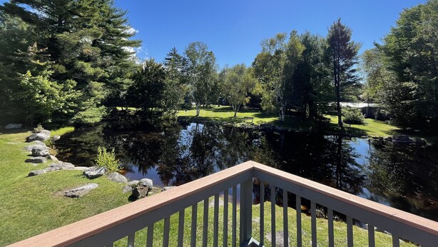 A serene lakeside view with a wooden deck, a grassy area, and a variety of trees. - Family Friendly Mountain Townhouse in N. Woodstock (Woodstock)