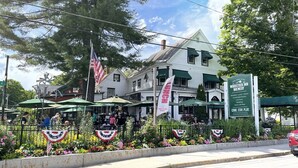 A restaurant with outdoor seating, a sign for Woodstock Inn Brewery, and American flags. - Family Friendly Mountain Townhouse in N. Woodstock (Woodstock)