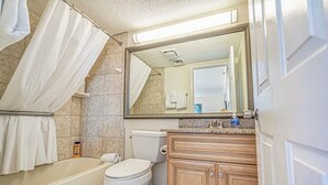 Une salle de bain avec une baignoire, des toilettes et un meuble-lavabo en bois.