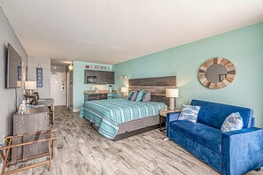 A bedroom with a bed, a blue sofa, a wooden floor, a wall clock, and a sign reading "SALTY AIR DR".