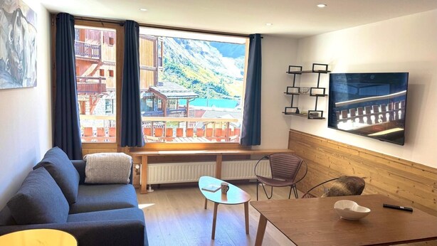 Una habitación acogedora con un ventanal grande, un sofá, una mesa de comedor y un televisor.