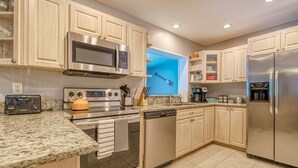 Una cocina moderna con electrodomésticos de acero inoxidable, encimeras de granito y muebles de madera clara.