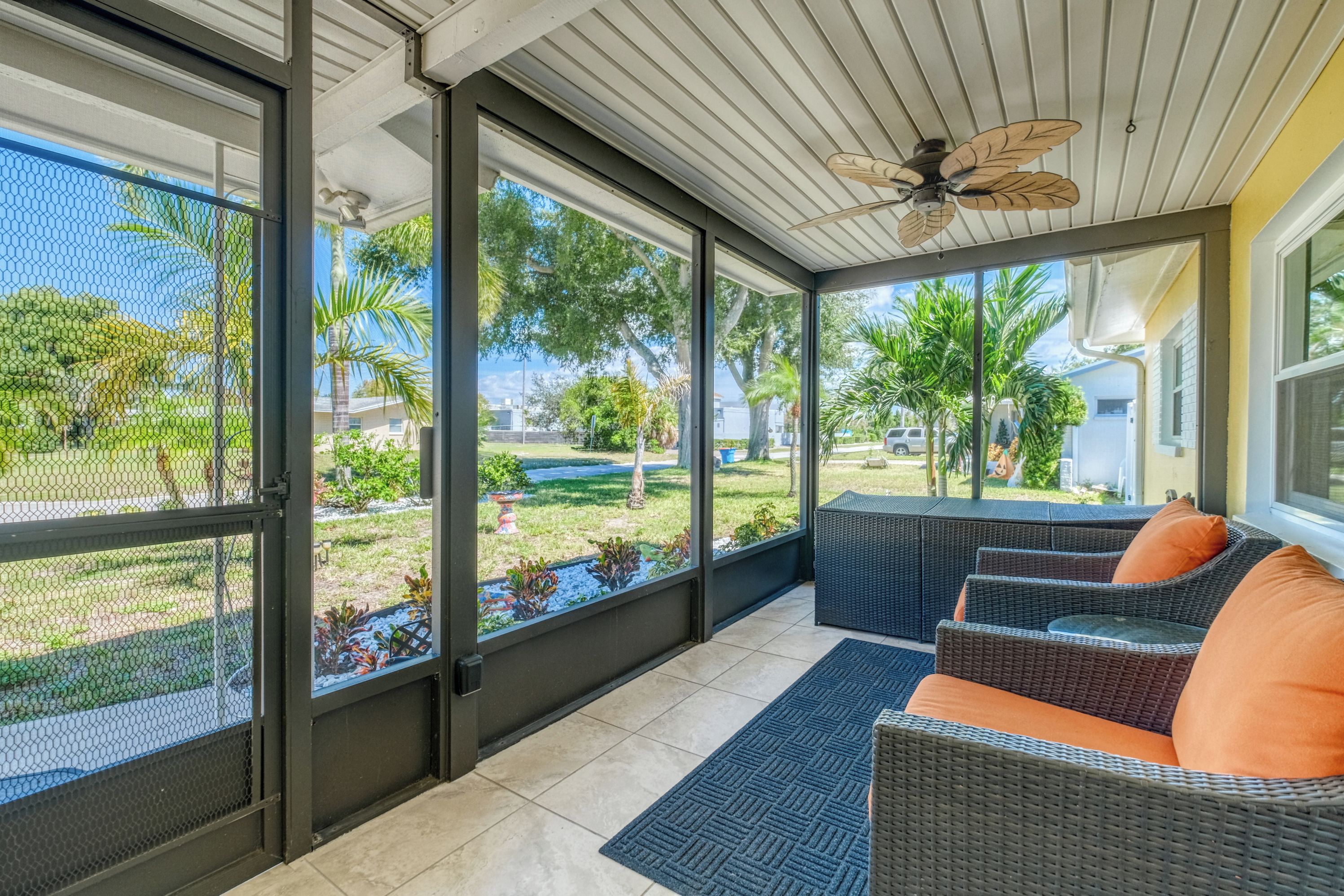 Un patio techado con muebles de mimbre y vista a un jardín ajardinado.