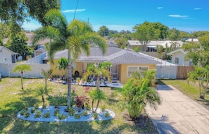 A residential area with single-story houses, a driveway, and a well-maintained lawn with palm trees.