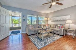 A living room with a gray sectional sofa, a coffee table, and a ceiling fan.