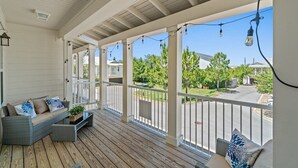 A covered porch with a wooden floor, white railings, and string lights. - Destin Family Beach Townhouse (Destin)