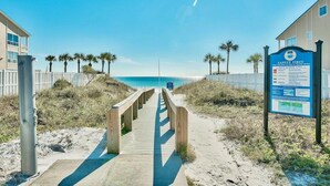 A wooden boardwalk leading to a beach with a safety sign on the right. - Destin Family Beach Townhouse (Destin)