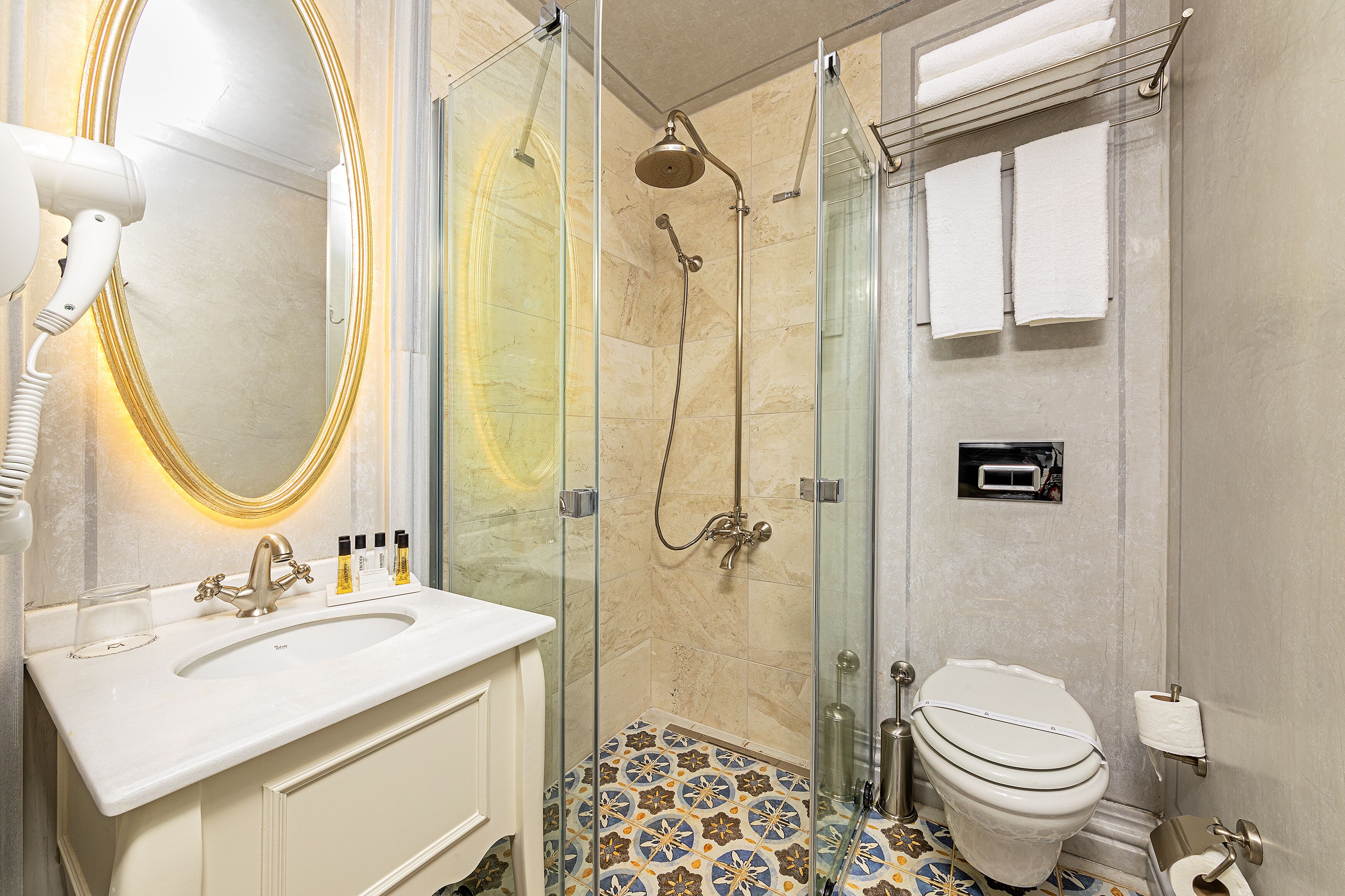 A bathroom with a glass-enclosed shower, a white sink, and a toilet.