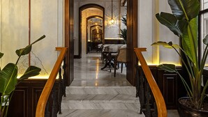A grand marble staircase with ornate railings, leading to a well-lit dining area with tables and chairs. - Meroddi Barnathan Hotel (Istanbul)