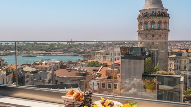 A balcony table with a variety of breakfast items and a view of a historic tower. - Meroddi Barnathan Hotel (Istanbul)