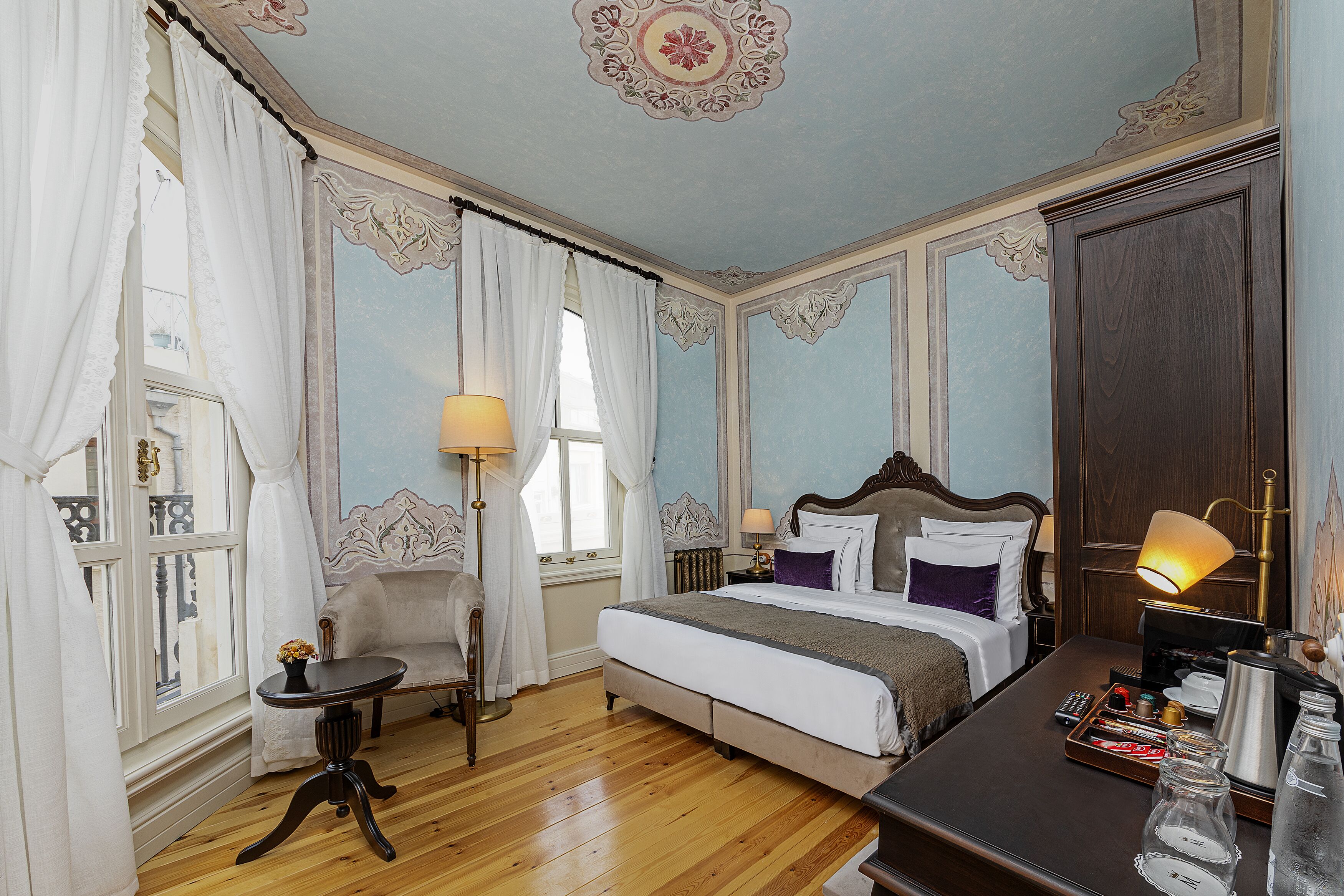 Una habitación de hotel con cama, mesita de noche, lámpara y una pequeña mesa con una silla.