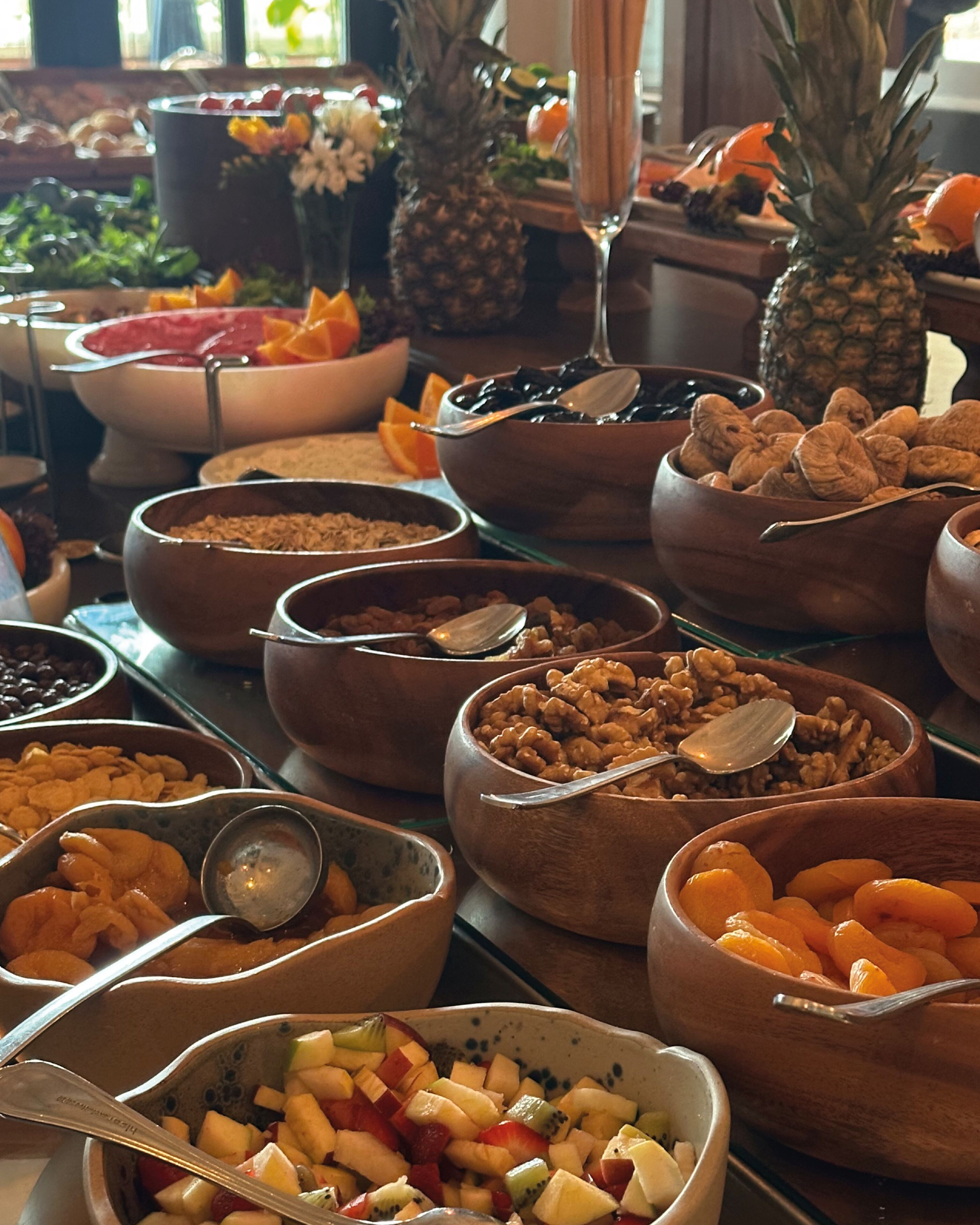 A buffet with various food items in bowls, including fruits, nuts, and other snacks.