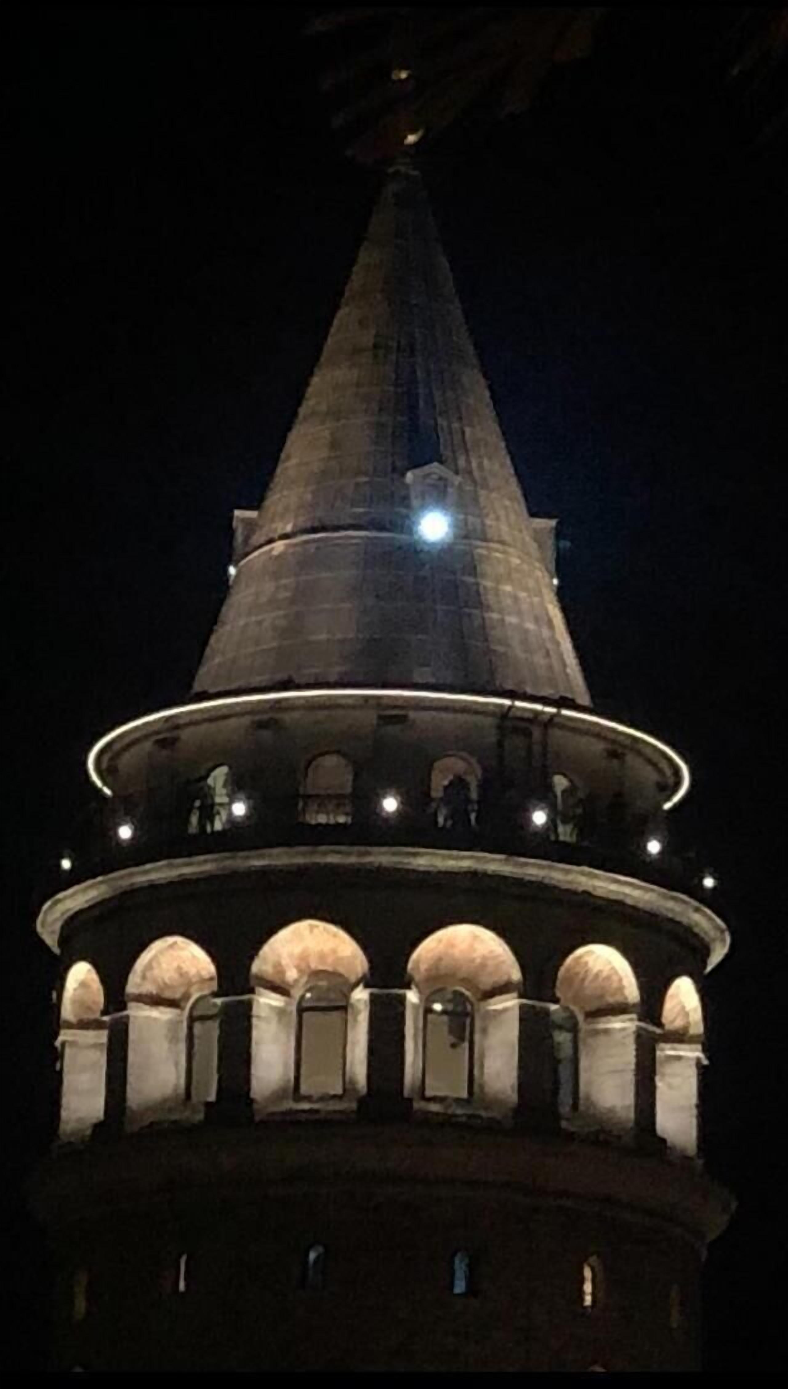 A tower with a conical roof and a circular base with arched windows.