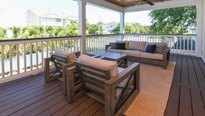 Une terrasse extérieure couverte, aménagée avec du mobilier en bois, un canapé et offrant une vue sur le quartier.