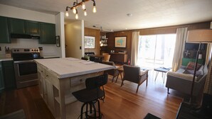 A spacious kitchen with a large island, wooden cabinets, and a dining area with a sofa and chairs. - Great Fishing, Gorgeous Views, Private Cabin on Pelican Lake (Orr)