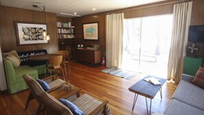 A cozy living room with a green sofa, a wooden coffee table, and a bookshelf filled with books. - Great Fishing, Gorgeous Views, Private Cabin on Pelican Lake (Orr)