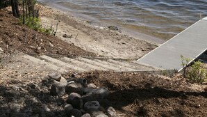 A lakeside view with a concrete dock extending into the water, surrounded by trees and rocks. - Great Fishing, Gorgeous Views, Private Cabin on Pelican Lake (Orr)