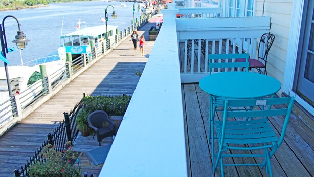 A wooden deck with a railing, a table, and chairs.